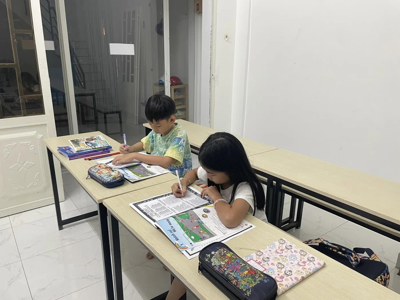 Hai bạn nhỏ luyện tập với sách và vở